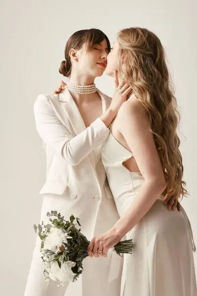 Duas noivas jovens em trajes de casamento branco abraçar durante a sua cerimônia, seu amor evidente em seu olhar amoroso. — Fotografia de Stock