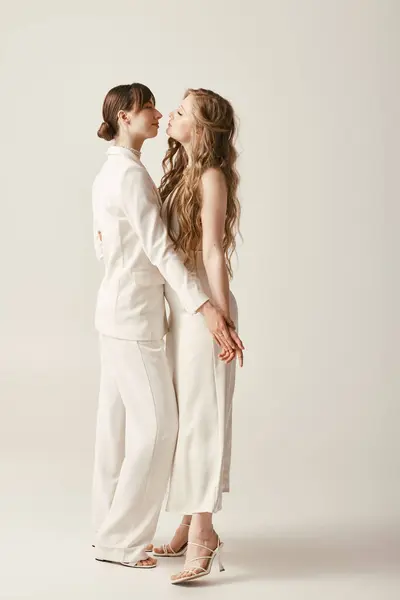 Two beautiful brides in white attire embrace during their wedding ceremony. — Stock Photo
