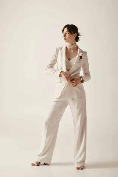 A beautiful bride poses in a white suit against a white background. — Stock Photo