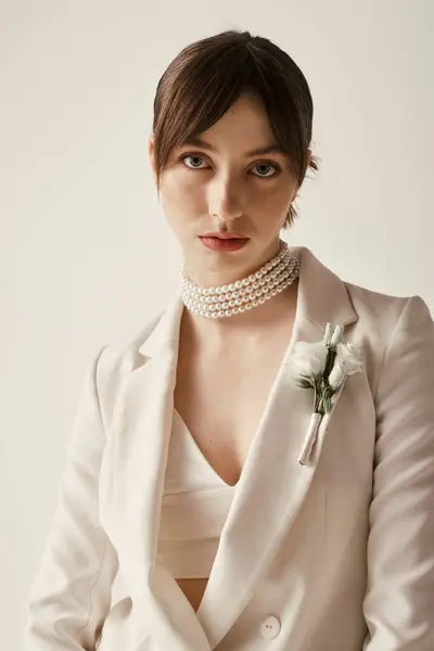 A beautiful bride wearing a white blazer with a pearl choker and a small white flower pinned to the lapel. — Stock Photo