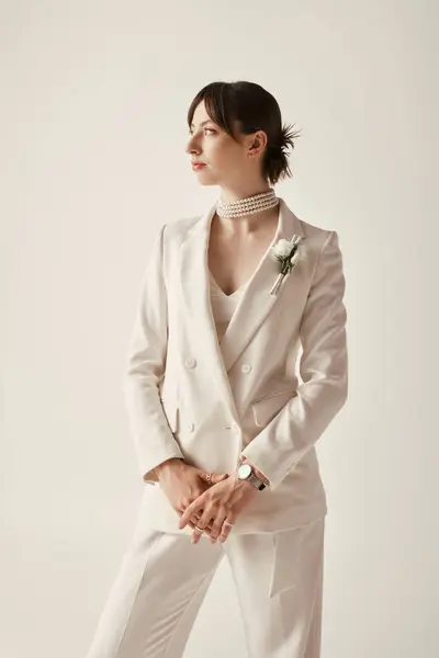 Una joven novia impresionante posa en una chaqueta blanca elegante y un collar de perlas, su estilo elegante cautivador. - foto de stock