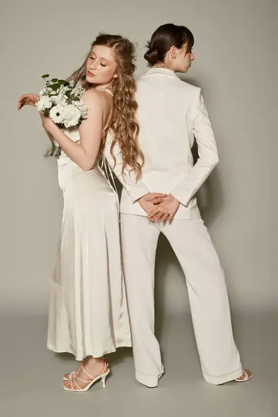 A lesbian couple in white wedding attire poses against a grey background, celebrating their love. — Stock Photo