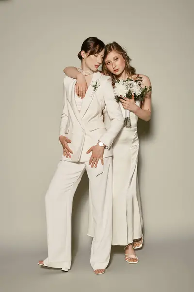 Un couple de lesbiennes en tenue blanche pose ensemble lors de leur cérémonie de mariage, célébrant l'amour LGBTQ. — Photo de stock