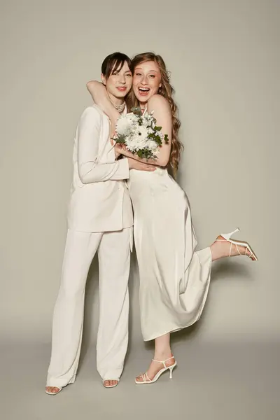 Una pareja lesbiana en traje de novia blanco abrazar y compartir una risa, celebrando su amor. - foto de stock