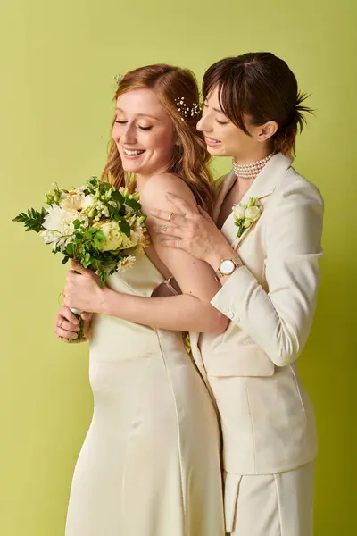 Duas noivas em trajes de casamento branco ficar juntos, abraçando, em um pano de fundo verde. — Fotografia de Stock