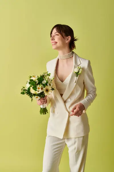 Una sposa in abito bianco tiene un mazzo di fiori mentre sorride. Lei è in piedi su uno sfondo verde. — Foto stock