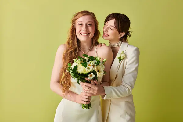 Two brides, dressed in white, share a joyous moment on their wedding day. The bride on the left holds a bouquet of white flowers, while the bride on the right has her arm around her partner. — Stock Photo