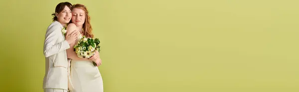 A lesbian couple in white wedding attire embraces against a green background, symbolizing their love and commitment. — Stock Photo