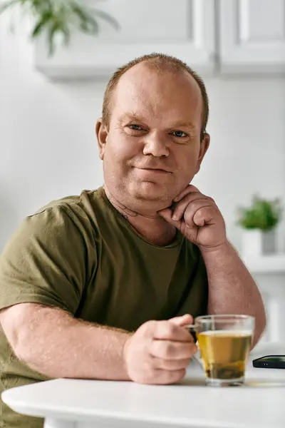 A man with inclusivity sits at home, casually dressed, enjoying a cup of tea. — Stock Photo