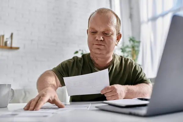 Un homme inclusif s'assoit à une table, examinant des documents. — Photo de stock