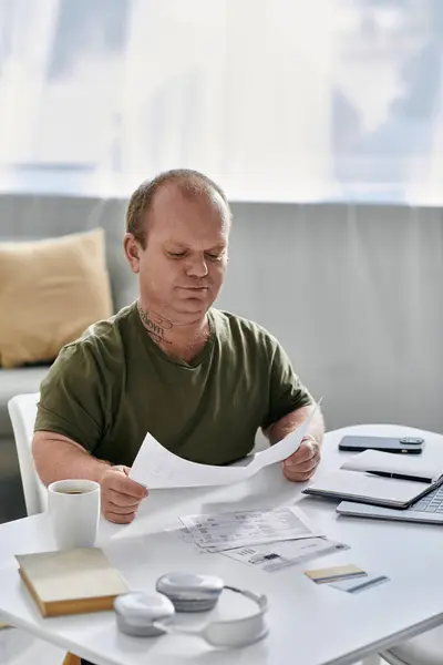 A man with inclusivity sits at a table in his home, reviewing documents. - foto de stock