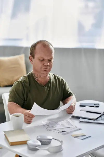 A man with inclusivity sits at a table in his home, reviewing documents. — Stock Photo