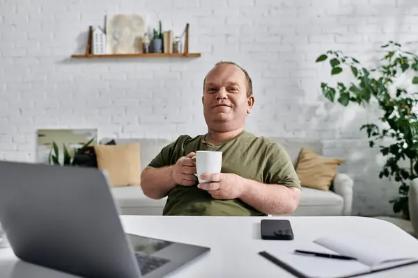 A man with inclusivity relaxes at home, enjoying a warm drink and the peace of his surroundings. — Stock Photo
