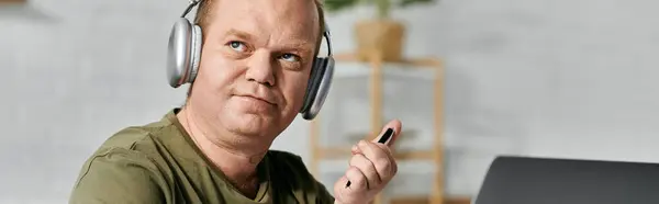A man with inclusivity relaxes at home, wearing headphones and casual clothing. — Stock Photo
