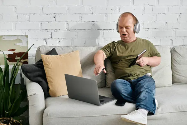 A man with inclusivity sits on a couch in a casual setting, working on a laptop. — Stock Photo