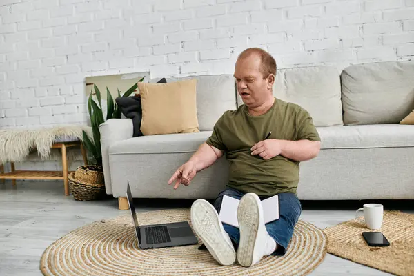 Um homem com inclusividade senta-se casualmente no chão em sua sala de estar, usando um laptop. — Fotografia de Stock