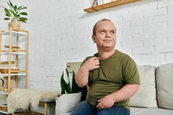 A man with inclusivity relaxes on a couch in his home, wearing casual attire. — Stock Photo