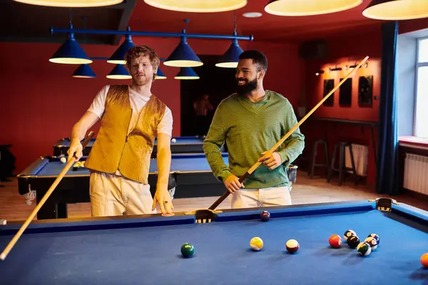 Friends play pool in a dimly lit room, one lining up a shot, the other looking on. — Stock Photo
