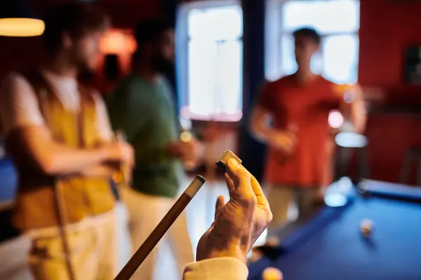 A group of friends casually play billiards in a dimly lit room. — Stock Photo