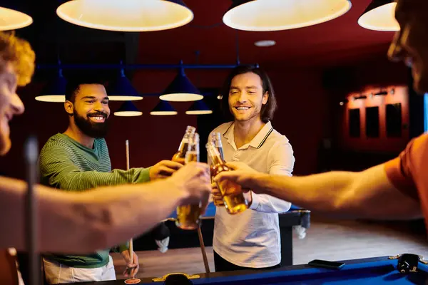 Gli amici alzano la birra in un brindisi dopo una partita a biliardo in un bar. — Foto stock