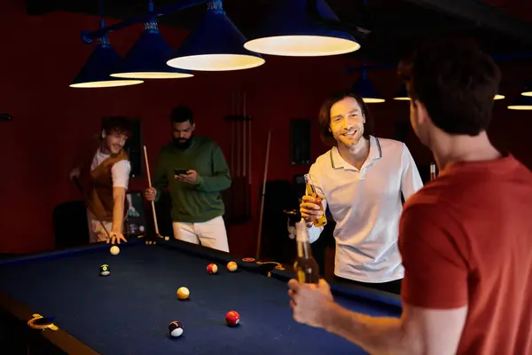 Un gruppo di amici gioca a biliardo in una stanza poco illuminata, sorseggiando drink e buona compagnia. — Foto stock