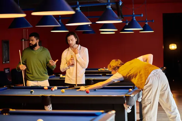 Friends enjoy a night out playing pool in a dimly lit room. — Stock Photo