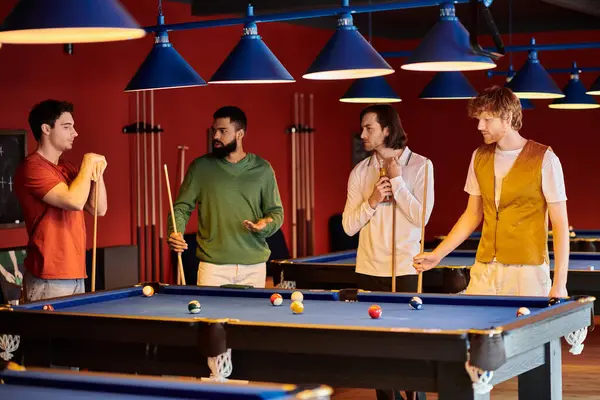 Quattro uomini vestiti con disinvoltura godono di una partita a biliardo in un club di biliardo scarsamente illuminato. — Foto stock