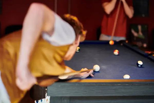 Un giovane schiera un tiro su un tavolo da biliardo, concentrandosi intensamente durante una partita amichevole con gli amici. — Foto stock