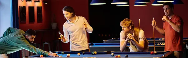Gli amici si divertono a giocare a biliardo in un pub scarsamente illuminato. — Foto stock