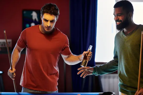 Friends play billiards and share a beer in a casual setting. — Stock Photo