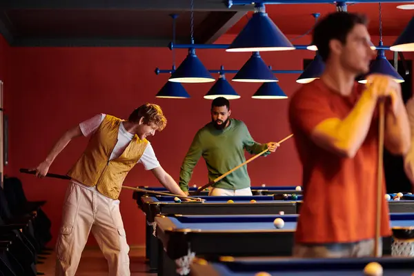 Friends play billiards in a dimly lit room, focused on the game. — Stock Photo