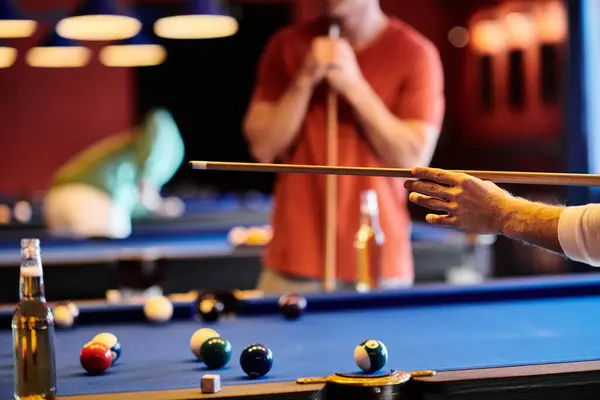 Friends gather for a game of billiards in a dimly lit setting. — Stock Photo