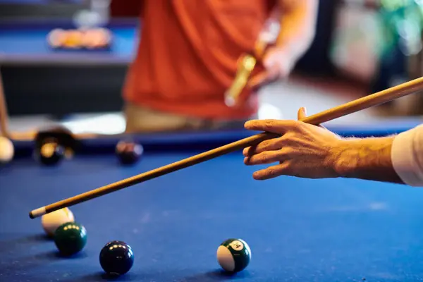 A close-up of a mans hand holding a pool cue, taking aim at the balls on the table. — Stock Photo
