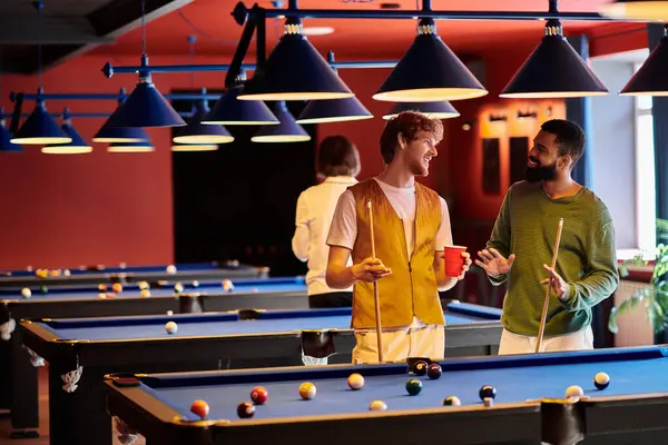 Friends play billiards in a dimly lit pool hall. — Stock Photo