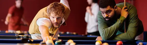 Friends play billiards together in a dimly lit pool hall. — Stock Photo