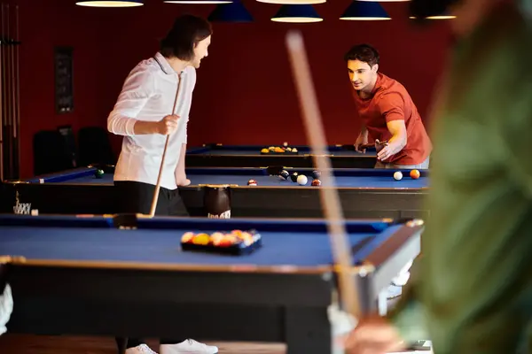 Friends play a game of billiards in a dimly lit bar, focusing on the game and enjoying their time together. — Stock Photo