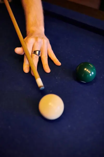 Una mano che tiene una stecca da biliardo, puntando a una palla bianca su un tavolo da biliardo in feltro verde. — Foto stock
