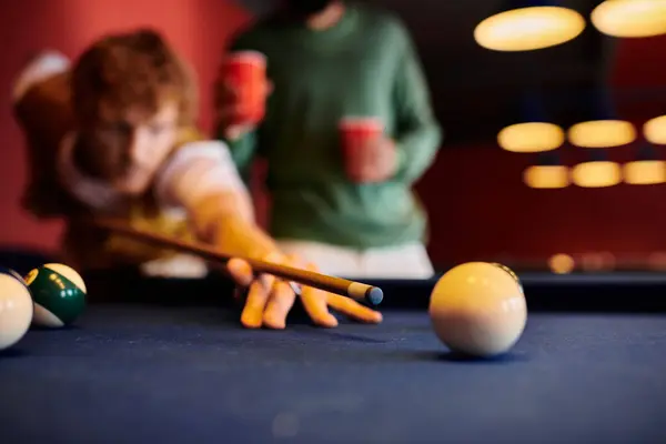 A player aims their cue stick at a billiard ball during a casual game with friends. — Stock Photo
