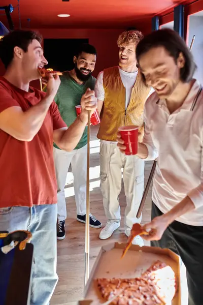 Amici riuniti intorno a un tavolo da biliardo, gustare pizza e bevande. — Foto stock