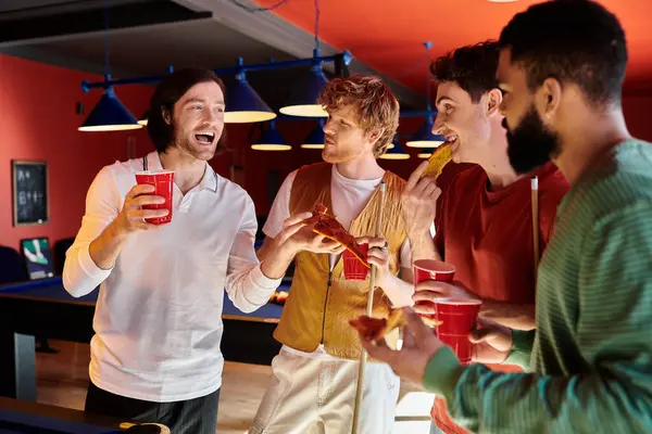 Friends stand around a pool table, enjoying food and drinks during a casual billiard game. — Stock Photo