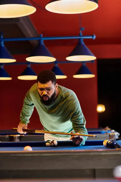 A man concentrates intently as he prepares to take a shot on the pool table. — Stock Photo