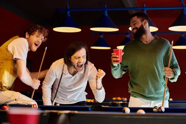 Friends celebrate a pool victory in a dimly lit room. — Stock Photo