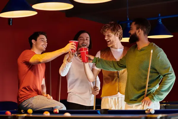 Friends raise their red cups in a toast during a relaxed billiards game. — Stock Photo