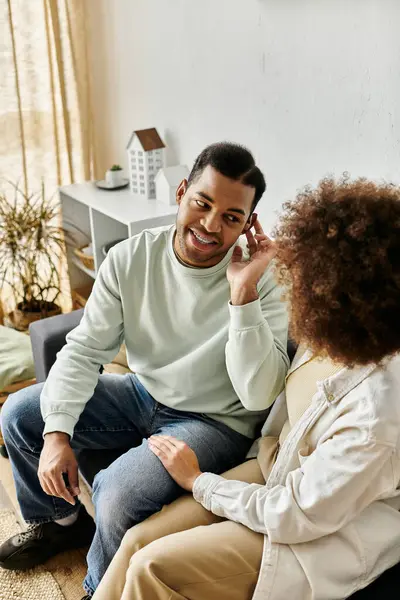 Um casal afro-americano senta-se junto em um sofá, língua de sinais para se comunicar. — Fotografia de Stock