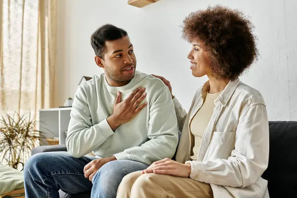 An African American couple sits on a couch, using sign language to communicate. — Stock Photo