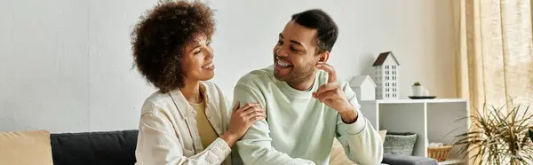 An African American couple sits on a couch at home, using sign language to communicate. — Stock Photo