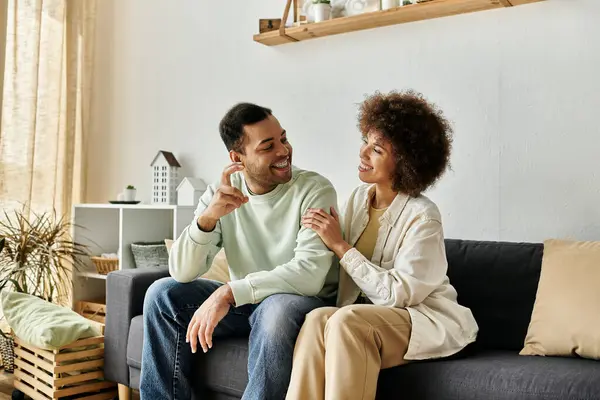 Una coppia afroamericana si siede su un divano, comunicando felicemente attraverso il linguaggio dei segni nella loro casa. — Foto stock