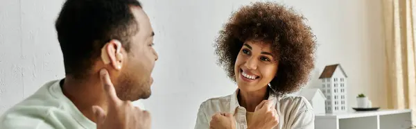 Um casal afro-americano sorrindo usa a língua de sinais para se comunicar em casa. — Fotografia de Stock