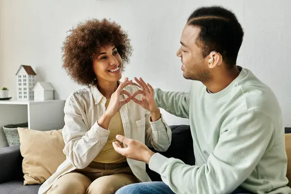Ein afroamerikanisches Paar kommuniziert mit Gebärdensprache, während es zu Hause auf einer Couch sitzt. — Stockfoto