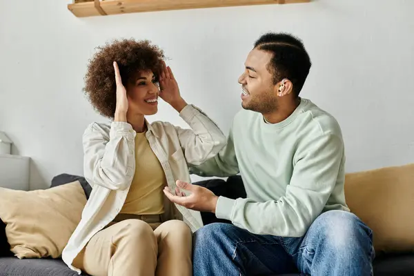 Una coppia afroamericana usa il linguaggio dei segni per comunicare mentre è seduta su un divano a casa. — Foto stock